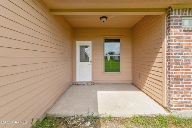 entrance to property featuring brick siding and a patio