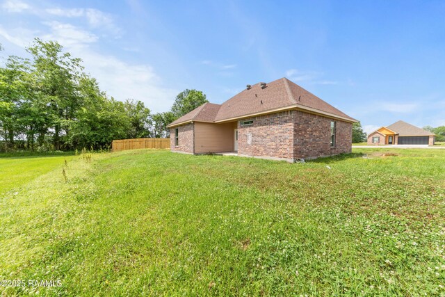 exterior space featuring a lawn, brick siding, and fence