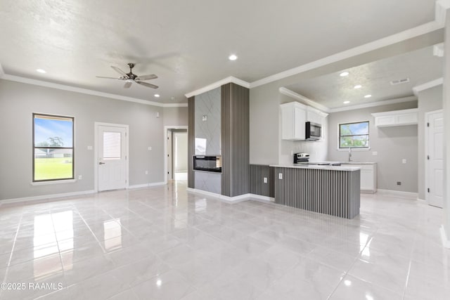 kitchen with crown molding, open floor plan, stainless steel microwave, white cabinetry, and recessed lighting