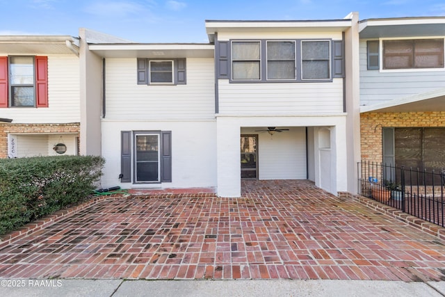 view of front of home with brick siding, ceiling fan, fence, and a patio