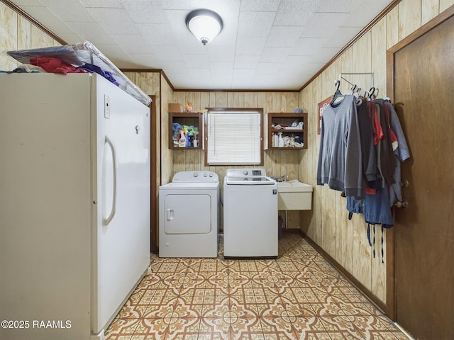 washroom featuring laundry area, separate washer and dryer, crown molding, and wood walls