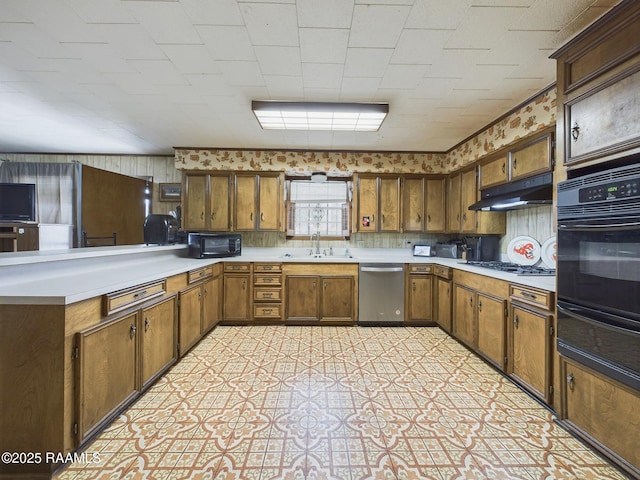 kitchen featuring light floors, under cabinet range hood, light countertops, black appliances, and a sink