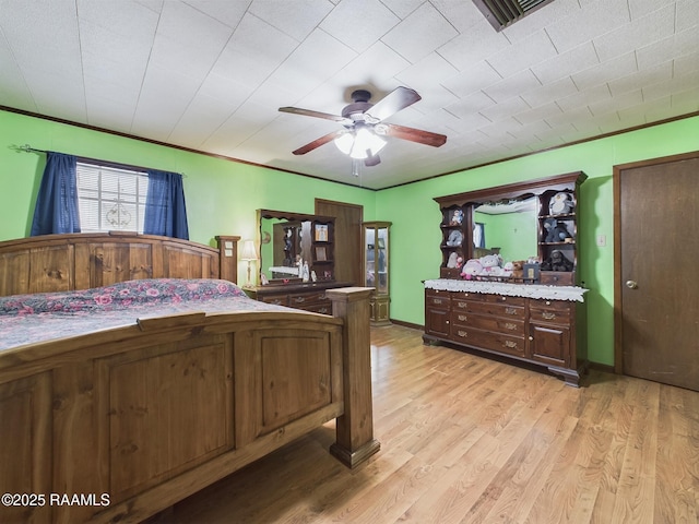 bedroom with a ceiling fan, light wood-type flooring, visible vents, and crown molding