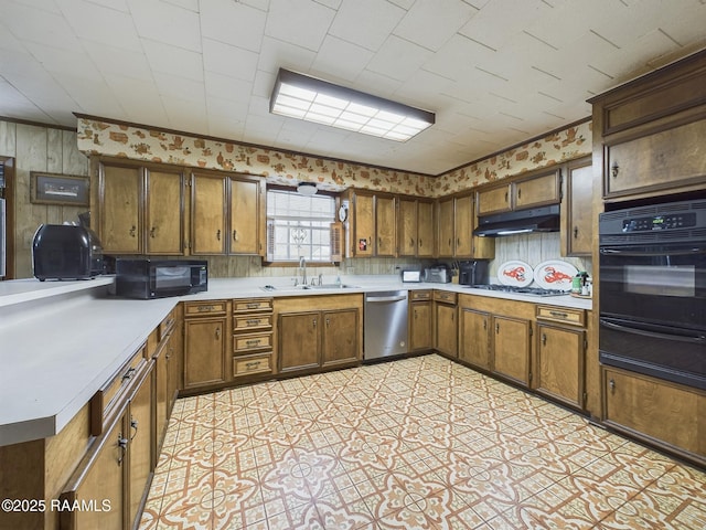 kitchen featuring a warming drawer, light countertops, a sink, under cabinet range hood, and black appliances