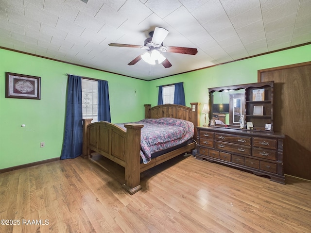 bedroom featuring ceiling fan, light wood-type flooring, baseboards, and crown molding