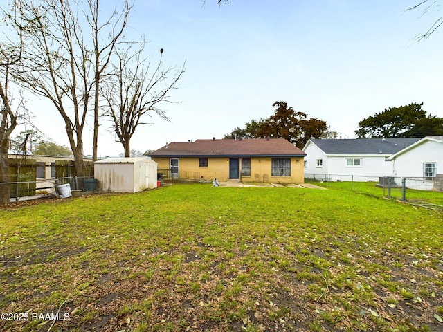 rear view of house featuring a yard, a fenced backyard, an outdoor structure, and a storage unit