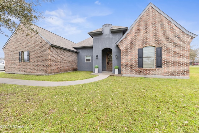 view of front of house featuring stucco siding, a front yard, and brick siding