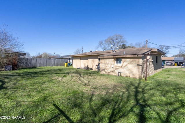 rear view of property featuring brick siding, fence, and a yard