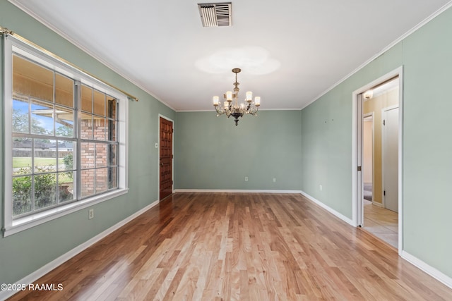 unfurnished room featuring baseboards, visible vents, ornamental molding, light wood-type flooring, and a chandelier