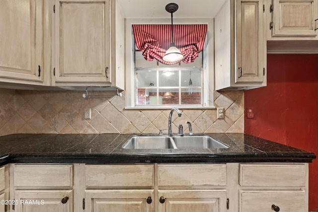 kitchen with dark countertops, backsplash, light brown cabinets, and a sink