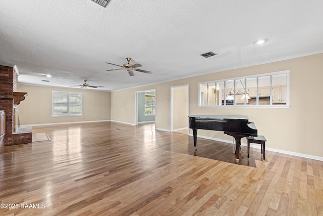 living area with visible vents, a brick fireplace, a textured ceiling, and wood finished floors