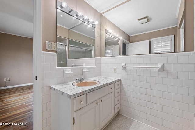 bathroom with vanity, wood finished floors, ornamental molding, wainscoting, and tile walls