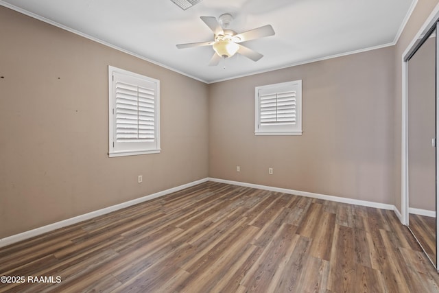 unfurnished bedroom with a closet, multiple windows, crown molding, and wood finished floors