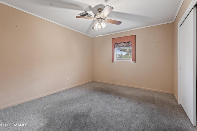 carpeted spare room featuring crown molding, a ceiling fan, baseboards, and visible vents