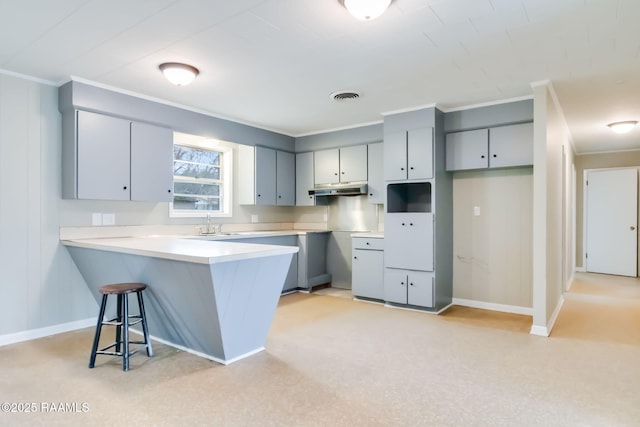 kitchen with visible vents, a peninsula, gray cabinets, light countertops, and under cabinet range hood