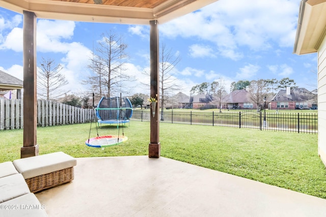 view of patio featuring a residential view, a trampoline, and a fenced backyard