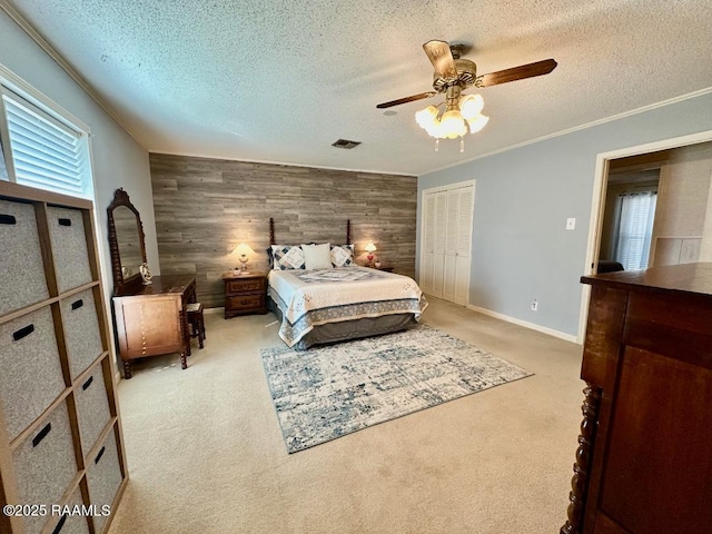 bedroom featuring crown molding, visible vents, an accent wall, light carpet, and wooden walls