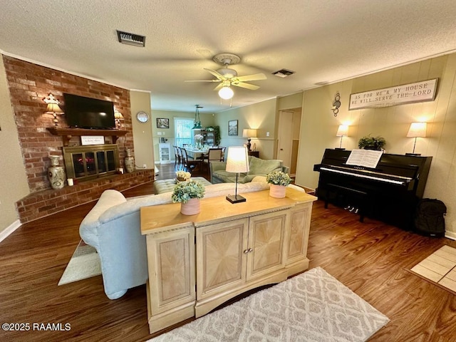 living room with visible vents, a fireplace, a textured ceiling, and wood finished floors