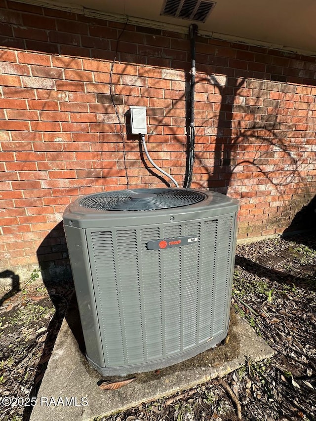 exterior details with brick siding, visible vents, and central air condition unit