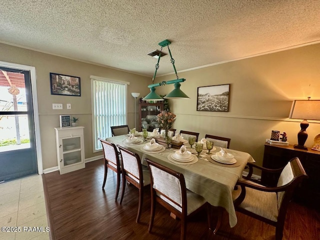 dining room with a textured ceiling, ornamental molding, and wood finished floors