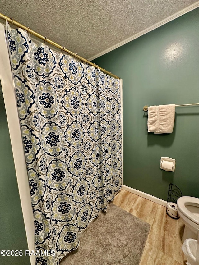 full bath with crown molding, toilet, a textured ceiling, wood finished floors, and baseboards