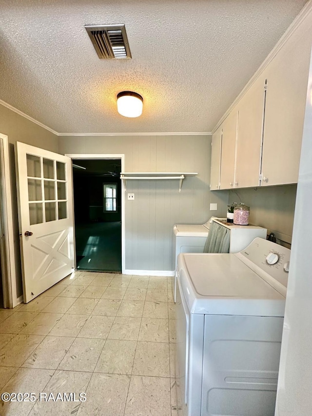 clothes washing area with ornamental molding, washing machine and dryer, cabinet space, and visible vents