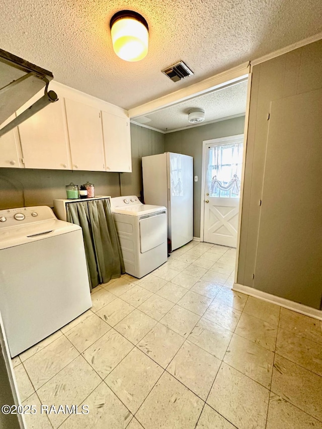 washroom with a textured ceiling, visible vents, baseboards, cabinet space, and washing machine and clothes dryer