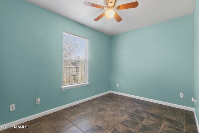 unfurnished room with stone finish floor, ceiling fan, and baseboards