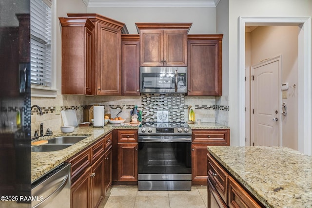 kitchen featuring light stone countertops, crown molding, stainless steel appliances, and a sink