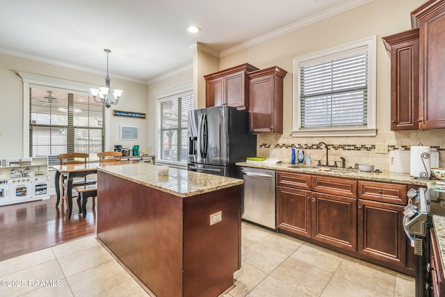 kitchen featuring a kitchen island, a sink, appliances with stainless steel finishes, decorative backsplash, and pendant lighting