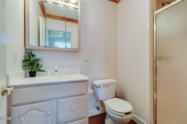 bathroom with a shower stall, toilet, vanity, and baseboards