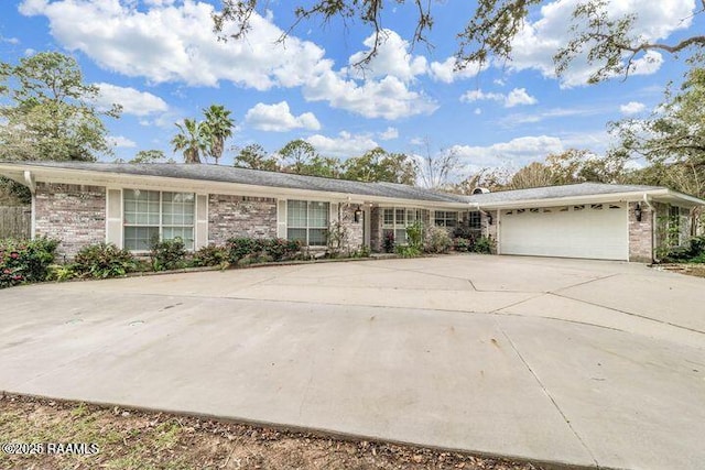 single story home with driveway, brick siding, and an attached garage