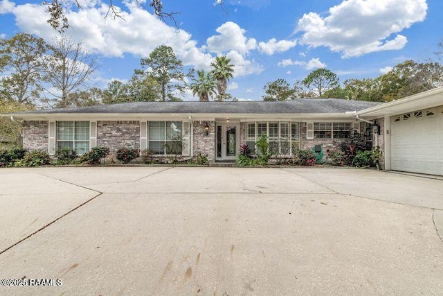 single story home featuring brick siding, an attached garage, concrete driveway, and french doors