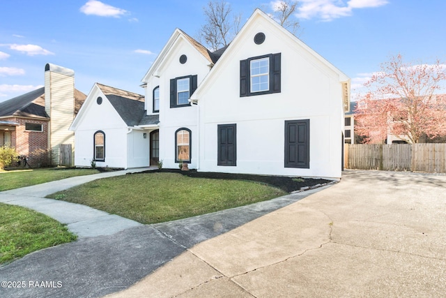 view of front facade with a shingled roof, fence, a front lawn, and stucco siding