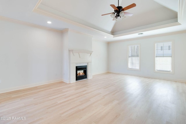 unfurnished living room featuring a lit fireplace, a raised ceiling, and crown molding