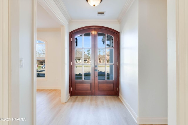 entryway with visible vents, arched walkways, crown molding, french doors, and light wood-type flooring