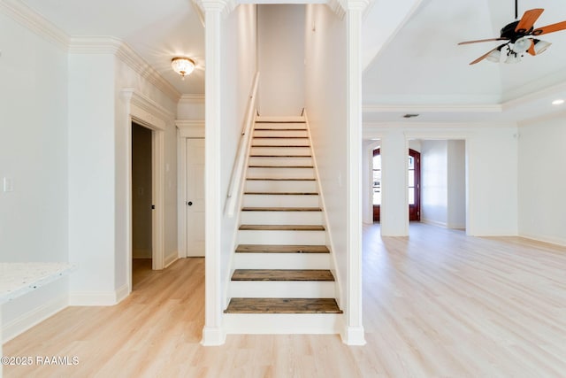 stairs with decorative columns, ornamental molding, a ceiling fan, wood finished floors, and baseboards