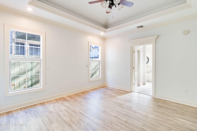 unfurnished room with a wealth of natural light, a tray ceiling, and light wood-style floors