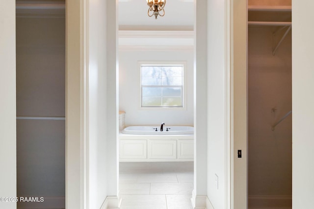 bathroom featuring a garden tub, a walk in closet, and tile patterned floors