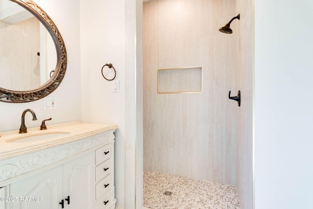 bathroom featuring tiled shower and vanity