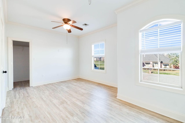 spare room with light wood-type flooring, visible vents, crown molding, and baseboards