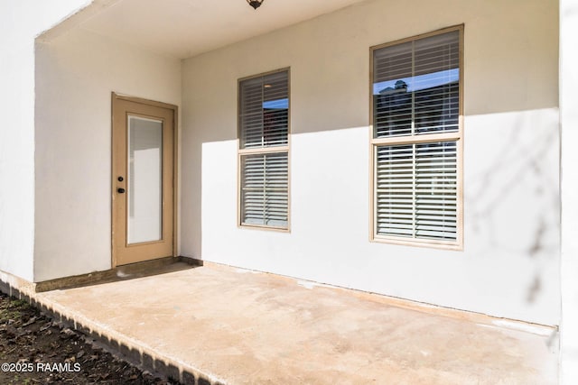 view of exterior entry featuring a patio and stucco siding