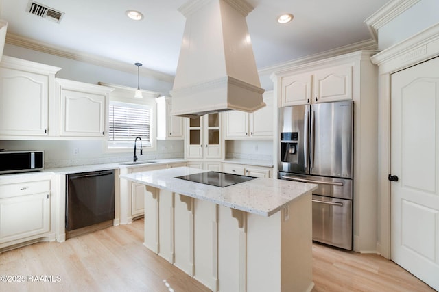 kitchen with a center island, custom exhaust hood, white cabinetry, a sink, and black appliances