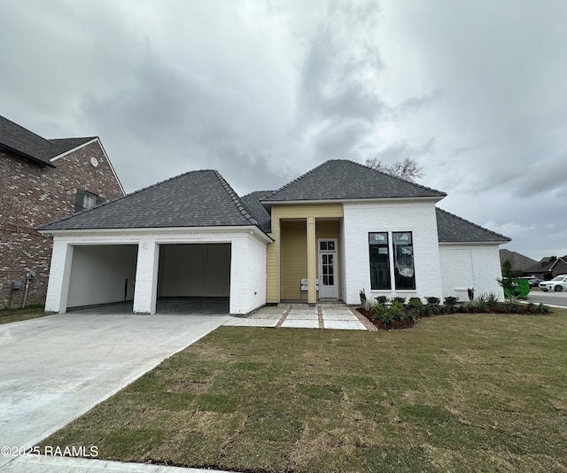 view of front of home with an attached garage, a shingled roof, concrete driveway, and a front yard