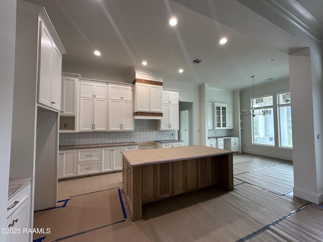 kitchen featuring visible vents, backsplash, white cabinetry, a kitchen island, and light wood-type flooring