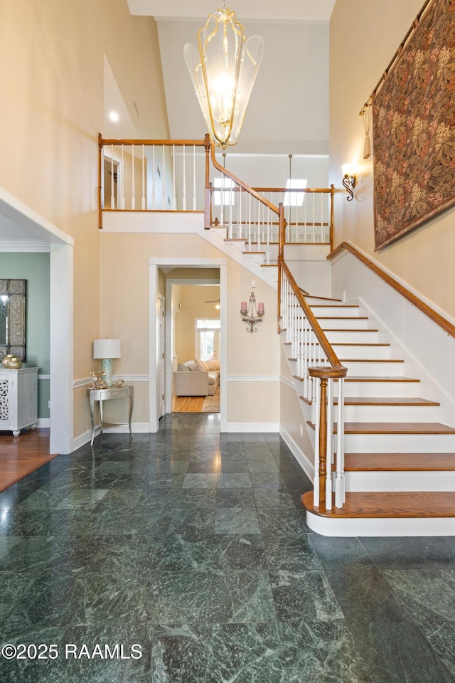 stairs featuring a high ceiling, baseboards, and a chandelier