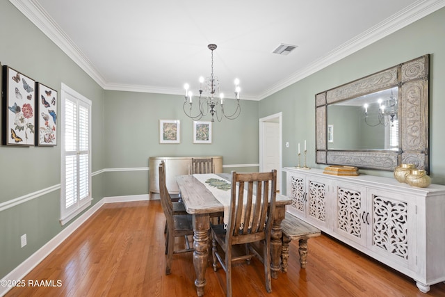 dining space featuring a chandelier, wood finished floors, visible vents, baseboards, and crown molding