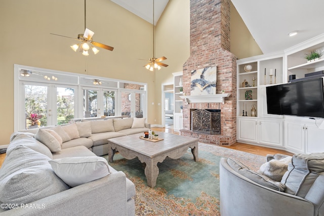 living room with built in features, french doors, a brick fireplace, high vaulted ceiling, and light wood-type flooring