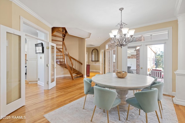 dining space featuring light wood-style floors, stairs, french doors, decorative columns, and crown molding