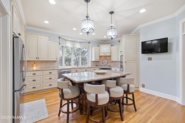 kitchen featuring a breakfast bar, appliances with stainless steel finishes, light stone countertops, light wood finished floors, and crown molding